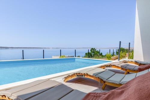 a swimming pool with lounge chairs and the ocean at Apartina - Sea view apartments in Rtina