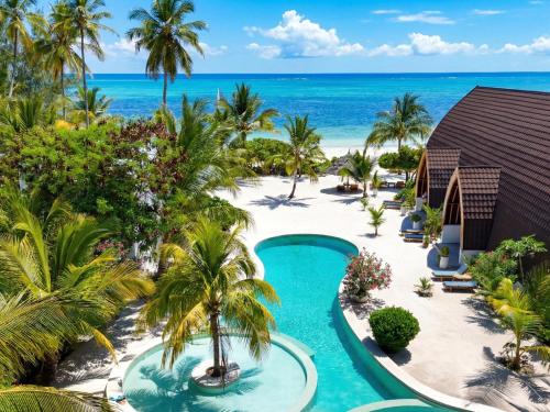 an aerial view of a resort with a pool and the ocean at Kijani Beach Villas in Bwejuu