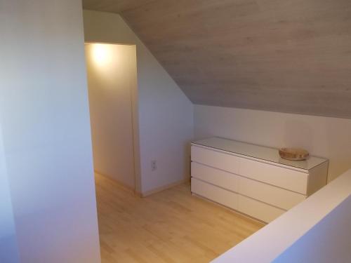 Cette chambre mansardée comprend une commode et une lampe. dans l'établissement Het Zolderhuis, à Arendonk