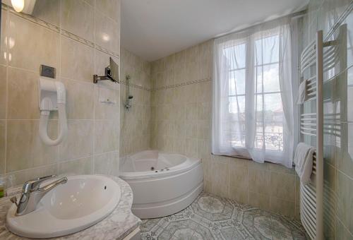 a white bathroom with a tub and a sink at Logis Le Tadorne in Piney