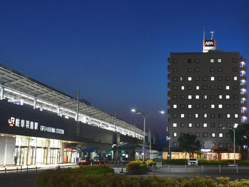 a building with a train on top of it at night at APA Hotel Gifu Hashima Ekimae in Hashima