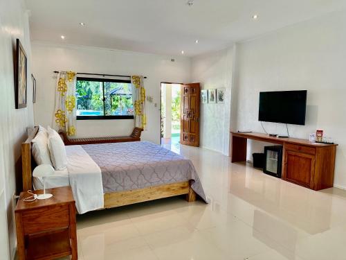 a bedroom with a bed and a flat screen tv at Strutz Art Garden Resort in Bangued