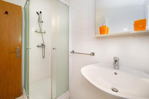 a white bathroom with a sink and a shower at Double Rooms Jasna with Sea View in Baška