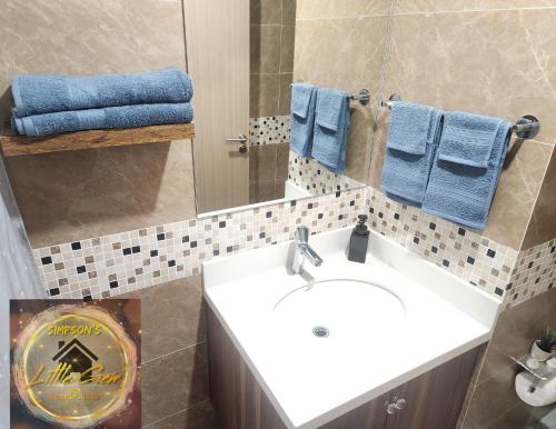 a bathroom with a sink and a mirror and blue towels at Simpsons Little Gem 2 in Kingston