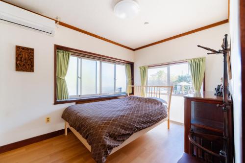 a bedroom with a bed and large windows at Wakamizu Minpaku in Tōgane