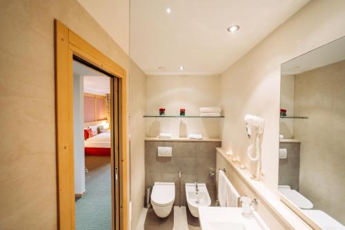 a bathroom with a toilet and a sink and a mirror at Schloss Hotel & Spa Pontresina in Pontresina