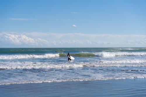 a person standing in the ocean with a surfboard at Wakamizu Minpaku in Tōgane