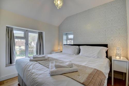 a bedroom with a large white bed with towels on it at 3 Bed in Croyde oc-yellow in Croyde