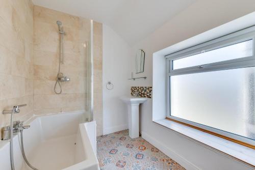 a bathroom with a tub and a sink and a window at 3 Bed in Croyde oc-yellow in Croyde