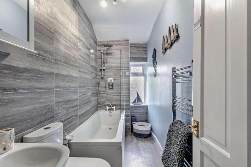 a bathroom with a tub and a toilet and a sink at 3 Bed in Dawlish oc-c29669 in Dawlish