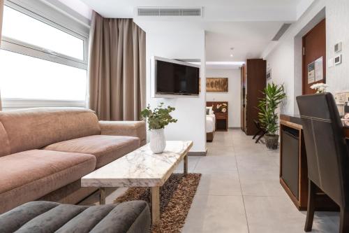 a living room with a couch and a tv at Achilleos City Hotel in Larnaca