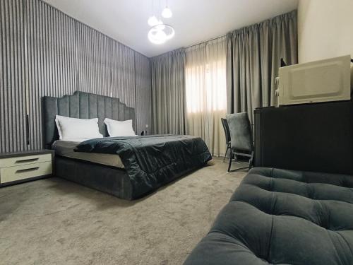 a bedroom with a bed and a tv and a couch at ApartHotel Rooms in Ajman