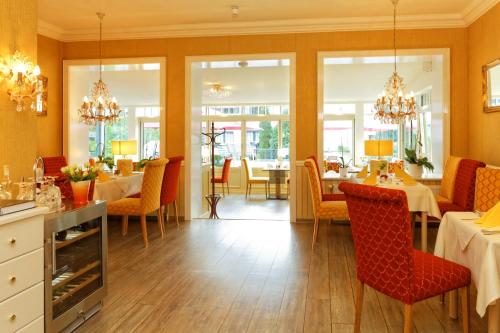a dining room with tables and chairs and chandeliers at Hotel Sonneneck in Zinnowitz