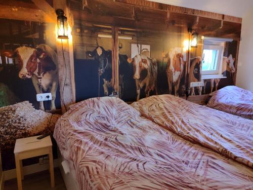 two beds in a room with paintings of cows on the wall at B&B Verwoldsehof 'Op de deel' in Laren