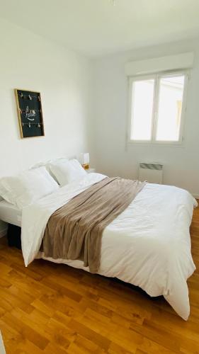 a white bed in a white bedroom with a window at Porte de Saint Emilion in Coutras