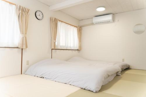 two beds in a room with a clock on the wall at one space 泊まれるコワーキングスペース in Kawatana