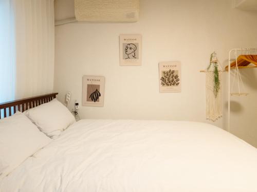 a bedroom with a white bed and pictures on the wall at Bandal Stay in Daegu in Daegu