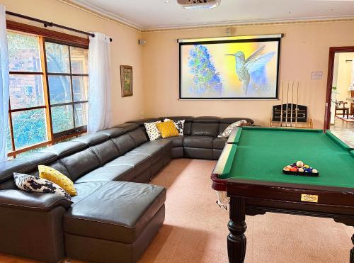 a living room with a couch and a pool table at Maggie's Guesthouse - large property with pool, billiards, tennis court, BBQ & more in Warrandyte