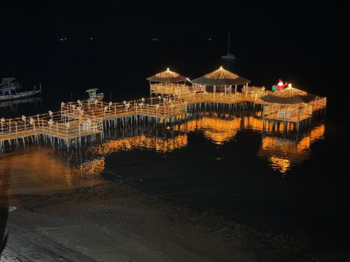 a dock with tables and umbrellas on the water at night at Hotel Cap du Sine Saloum in Ndangane