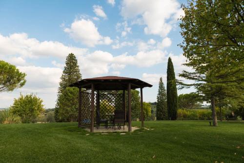 a gazebo with a bench in a grass field at Terra Antica - Resort, Winery & SPA in Montepulciano