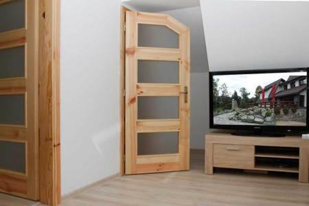 a room with a tv and a wooden book shelf at Penzion Réva in Jablunkov