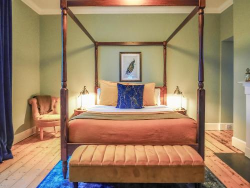 a bedroom with a canopy bed and a chair at Sancreed House B&B in Penzance