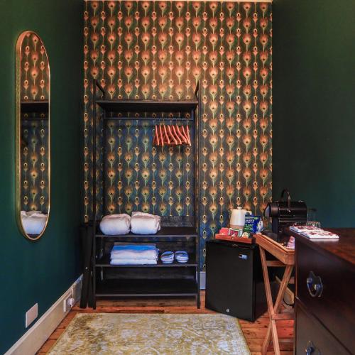 a room with a green wall with a shelf with towels at Sancreed House B&B in Penzance