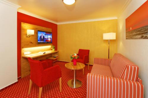a hotel room with a couch and a table and chairs at Hotel Sonneneck in Zinnowitz