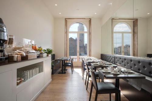 a dining room with tables and chairs and windows at 7Florence in Florence