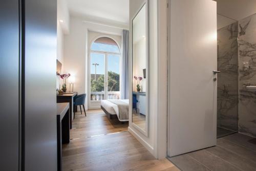 a corridor with a room with a bed and a mirror at 7Florence in Florence