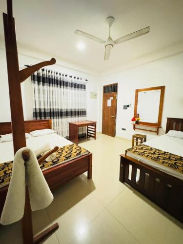 a hotel room with two beds and a mirror at Nimjaya holiday bunglow in Anuradhapura