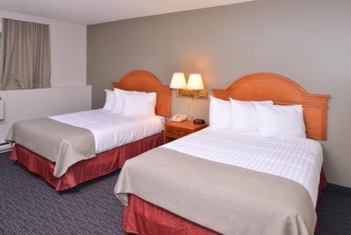 a hotel room with two beds and a phone at Rodeway Inn in Sudbury