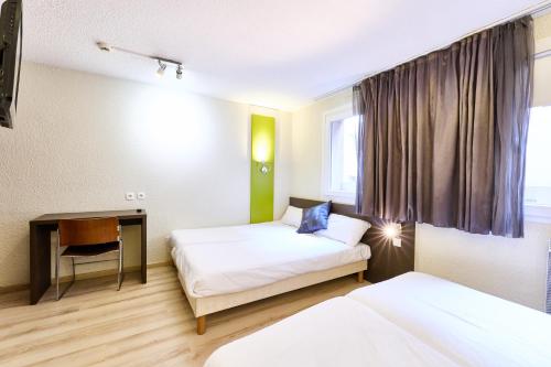 a hotel room with two beds and a desk at Cit'Hotel Primo Colmar Centre in Colmar