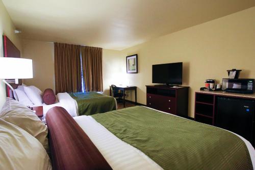 a hotel room with two beds and a flat screen tv at Cobblestone Hotel & Suites - Devils Lake in Devils Lake