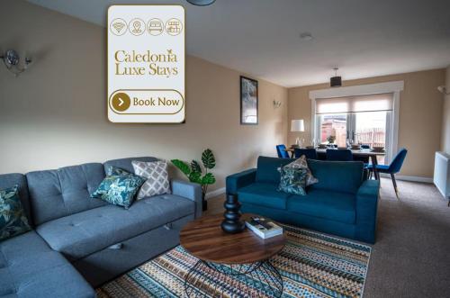 a living room with blue couches and a table at Skye House in Grangemouth