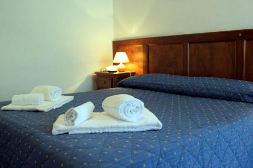 two beds with towels and pillows on them at Hotel La Quiete in Bardonecchia