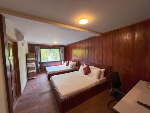 a bedroom with two beds and a desk in it at Sun & Roots Kampot Lodge in Kampot