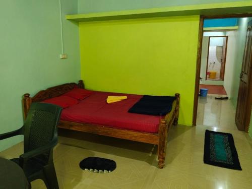 a bedroom with a red bed with a green wall at Sharvati Backwater Homestay in Haldipur