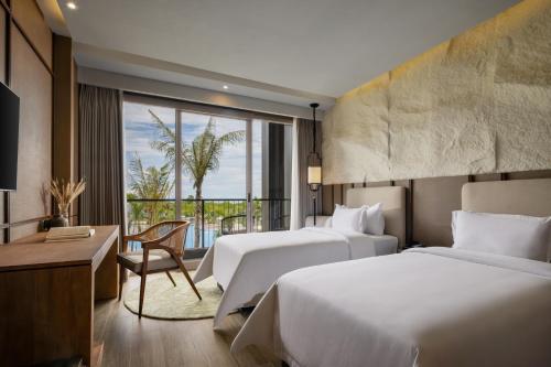a hotel room with two beds and a window at Myze Hotel Waingapu in Waingapu