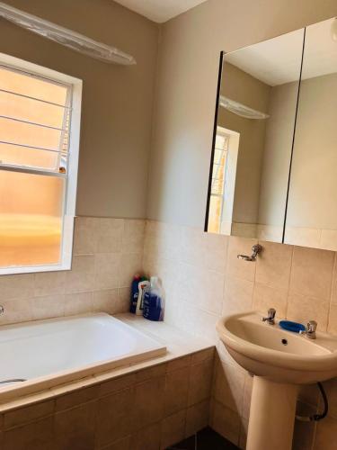 a bathroom with a tub and a sink and a mirror at Honeypot Ridge 29 in Honeydew