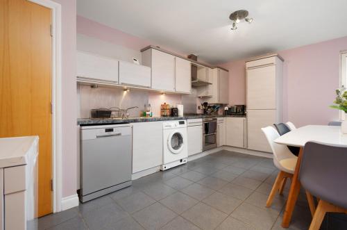a kitchen with white appliances and a table with chairs at 5 Bed Finnieston SkyHigh Duplex with Parking in Glasgow
