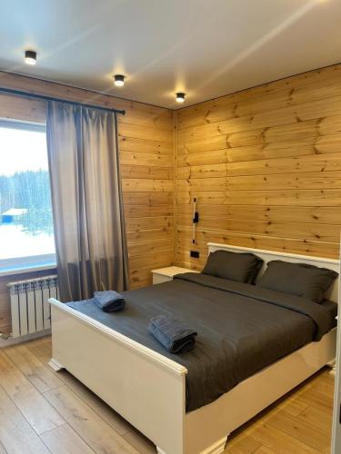 a bedroom with a large bed with a wooden wall at Forest Club Burabay in Zhezdi