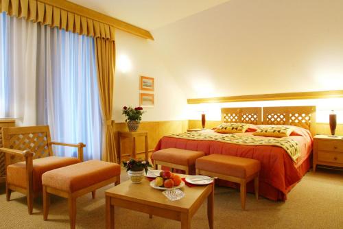 a hotel room with a bed and chairs and a table at King's and Lake's House Golf Course Royal Bled in Bled