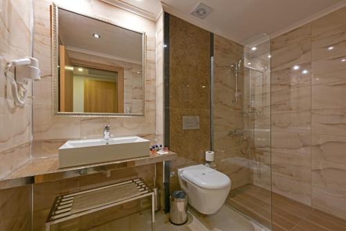 a bathroom with a sink and a toilet and a mirror at İncekum West Hotel -Ultra All Inclusive in Alanya