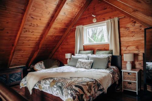 a bedroom with a bed in a log cabin at Breathe Glenrock Gardens in Tenterfield