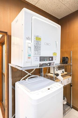 a kitchen with a large white appliance on top of a refrigerator at Soresta INN Shinozaki in Tokyo
