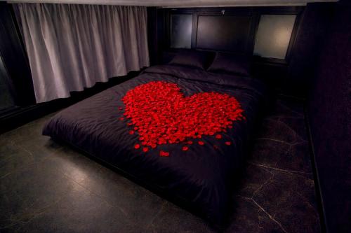 a bed with a pile of red hearts on it at Lasuitesecretetdetente in Beauvais