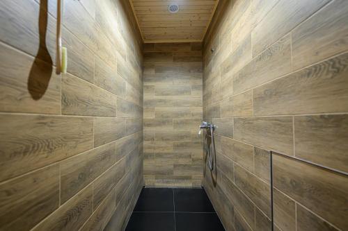 a bathroom with wooden walls and a walk in shower at Birdhouse in Prešov