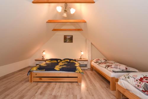 a attic bedroom with two beds and two lamps at Drevenica Matilda in Pribylina