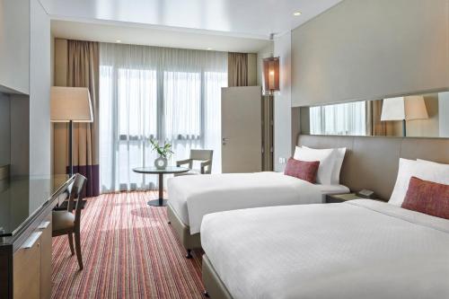 a hotel room with two beds and a table at Park Rotana Abu Dhabi in Abu Dhabi